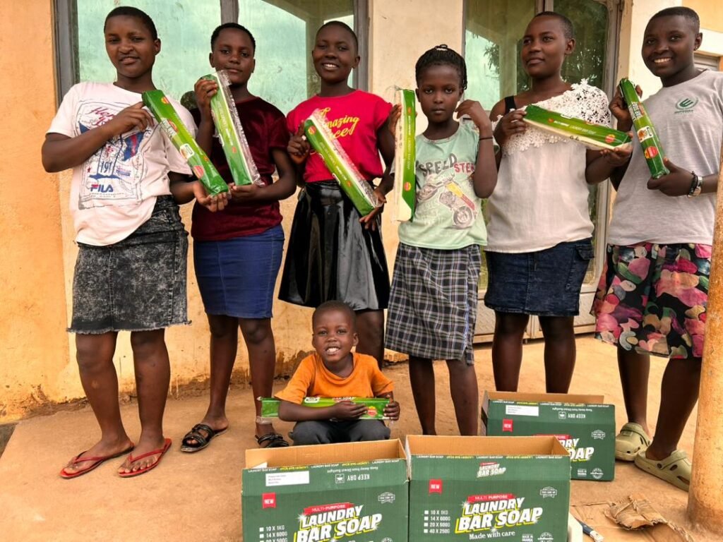 Young people from the district holding sleeved Jukye bars beside cases ready for distribution